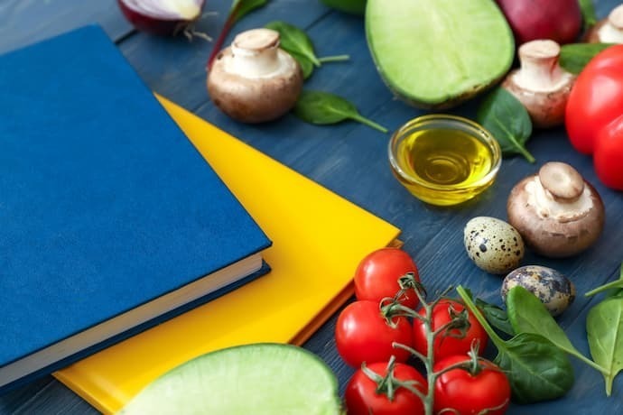 Livro azul com alimentos ao lado