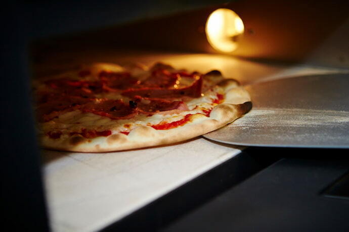 Pizza sendo colocada no forno bem de perto