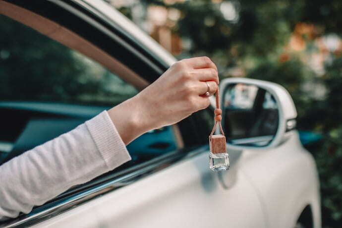 Alguém segurando um aromatizador para carro fora da janela