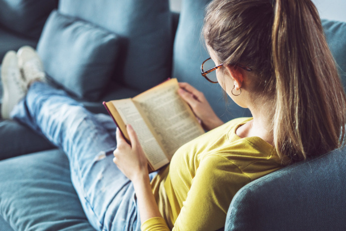 Mulher sentada no sofá lendo um livro