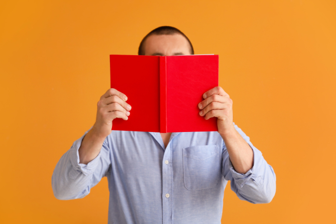 Homem lendo um livro com fundo laranja