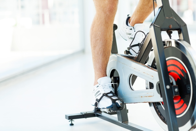 Indivíduo usando uma bicicleta ergométrica e com os pedais em foco