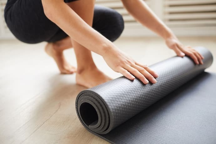 Mulher enrolando tapete de exercícios 