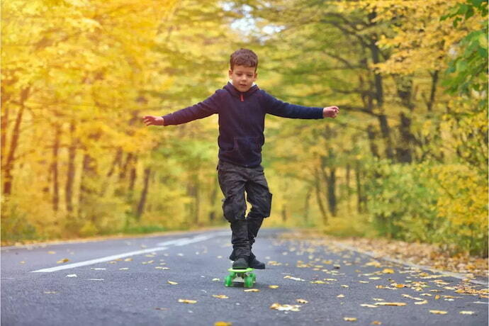 Menino se equilibrando sobre o skate, com braços estendidos